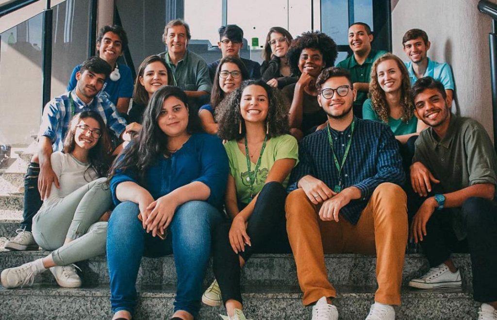 Jovens estudantes sentados juntos nos degraus da escada da faculdade.